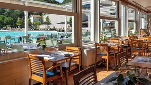 A restaurant with outdoor seating overlooking a pool and a clear view of the surrounding area. - Hôtel Lyon Métropole & Spa (Lyon)