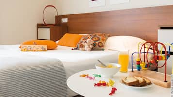 Habitación de hotel con cama, mesita de noche con artículos de desayuno, pared decorada con obras de arte y cabecero de madera.