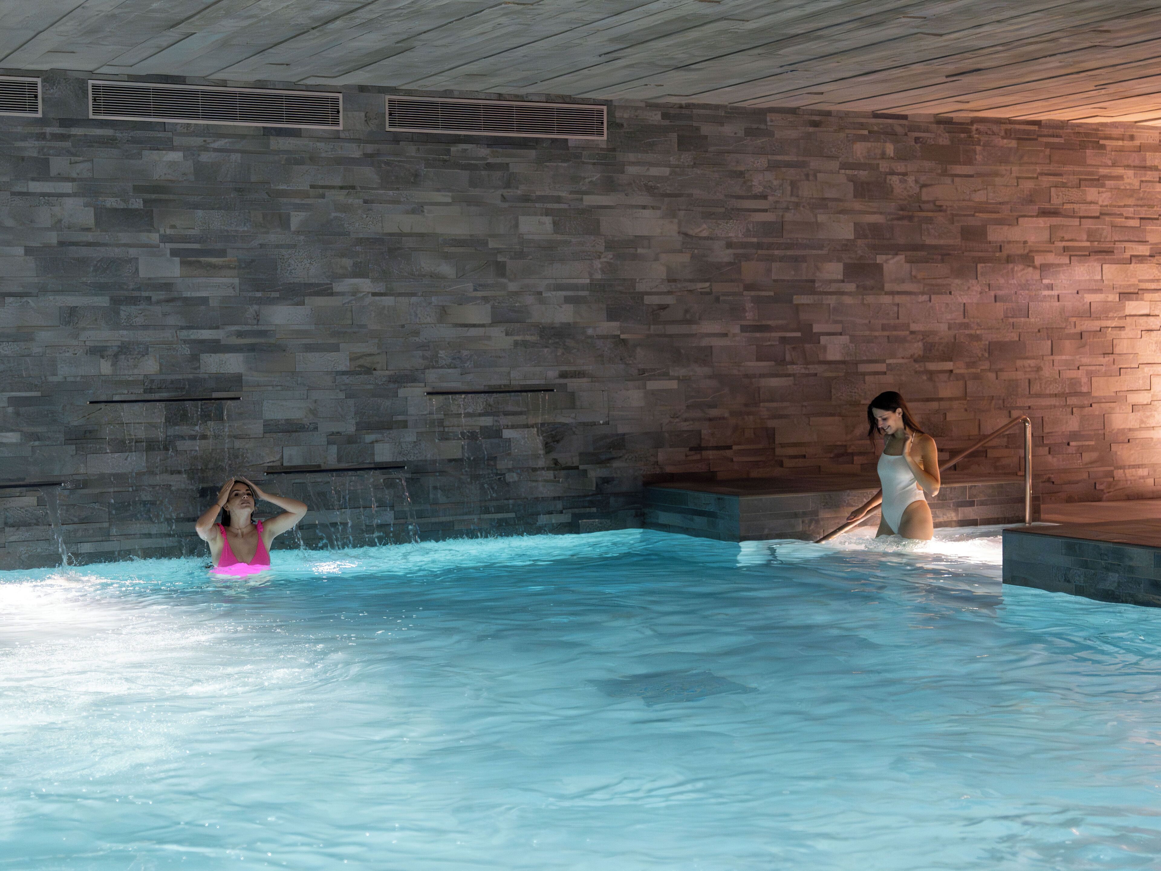 Une piscine intérieure avec des murs en pierre et un plafond en bois.