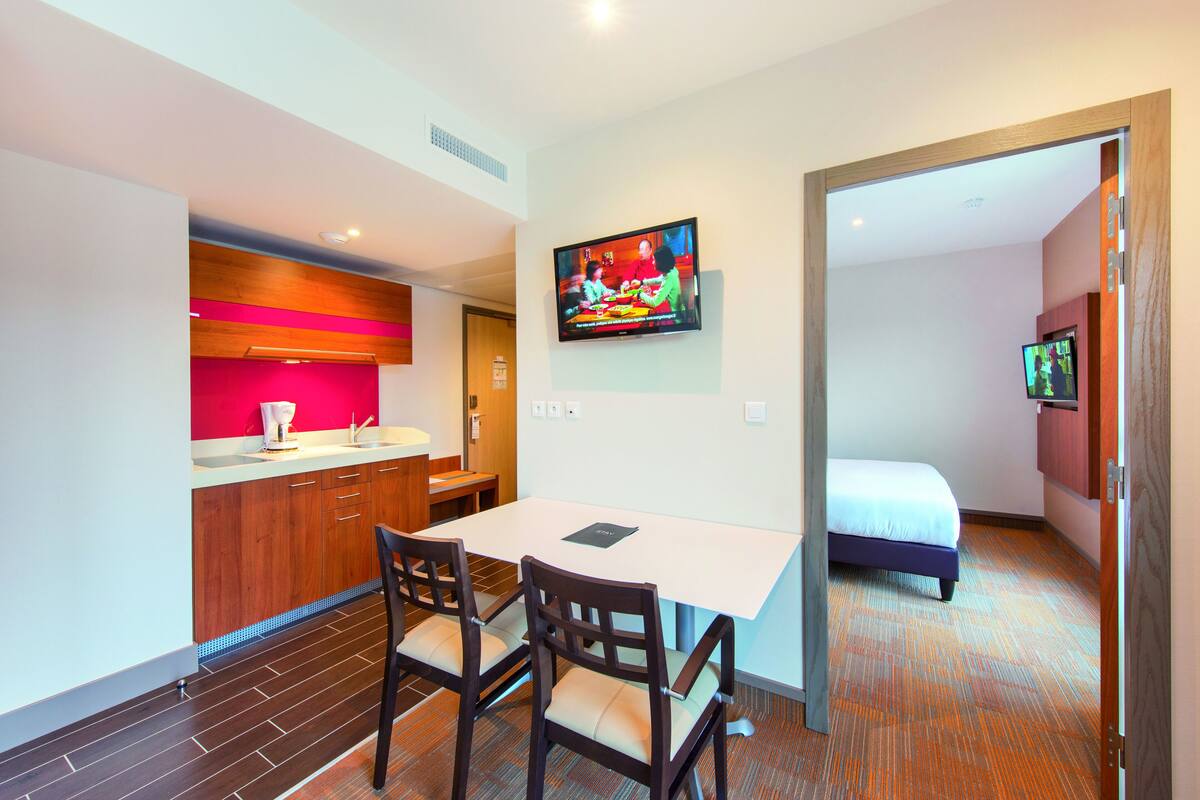 Une chambre d’hôtel compacte comprenant un coin cuisine, un espace repas et un lit.