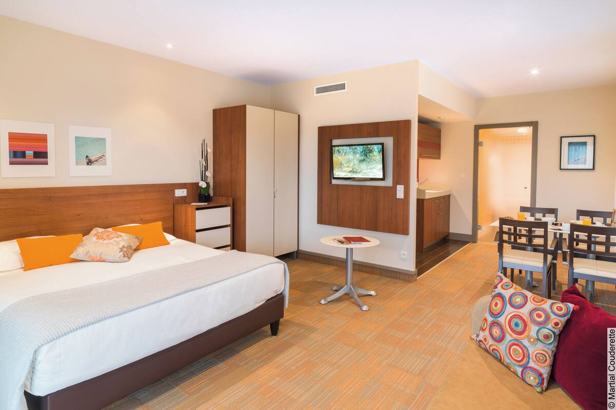 Une chambre d’hôtel comprenant un lit, une petite table, un téléviseur et un coin repas avec des chaises et une table.
