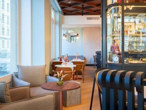 A modern interior with a seating area, a reception desk, and a view of the city through large windows. - Grand Hotel des Brotteaux Lyon Ctre - Handwritten Collection (Lyon)