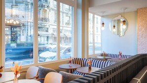 A modern interior with large windows, a curved bench seating area, and a round table with a vase. - Grand Hotel des Brotteaux Lyon Ctre - Handwritten Collection (Lyon)