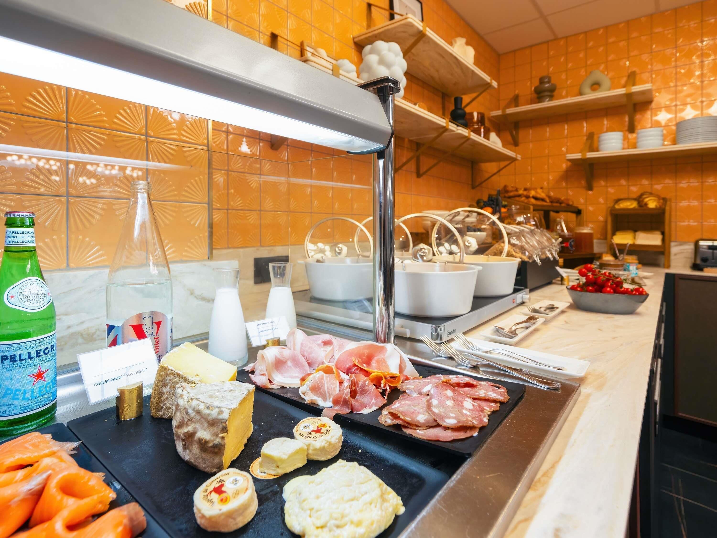 A buffet with various cheeses, cured meats, and a bottle of Pellegrino water.