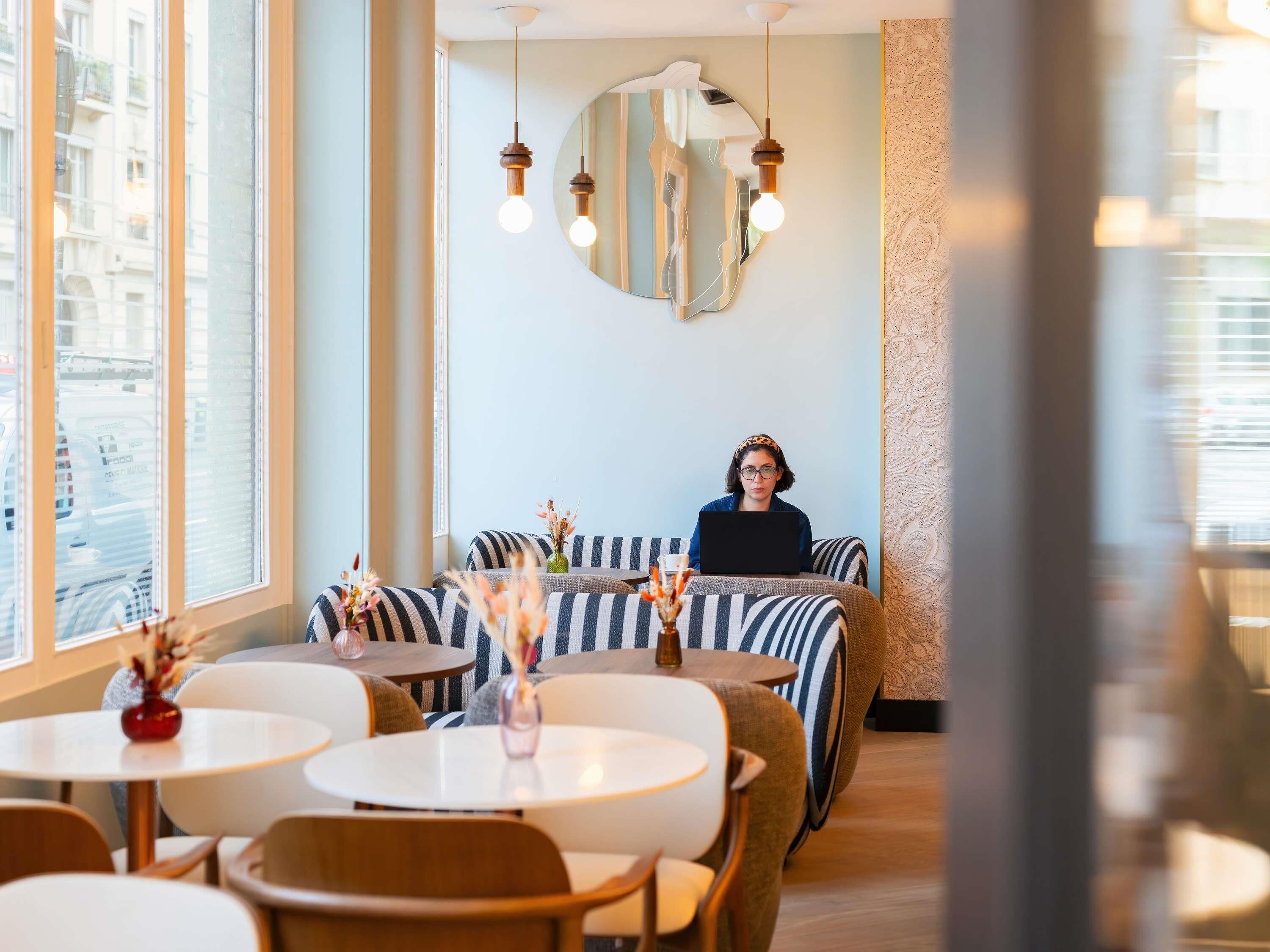 A modern interior with striped sofas, round tables, and hanging pendant lights.