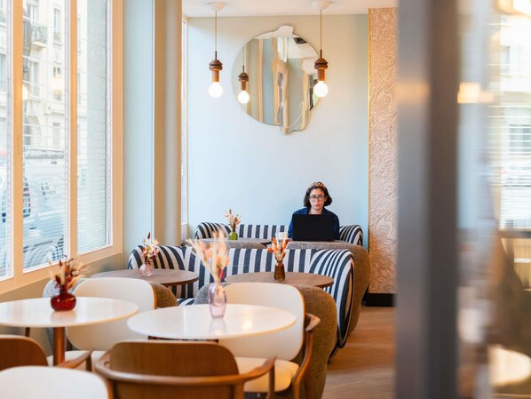 A modern interior with striped sofas, round tables, and hanging pendant lights. - Grand Hotel des Brotteaux Lyon Ctre - Handwritten Collection (Lyon)