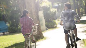 Twee personen fietsen op een verhard pad in een park.