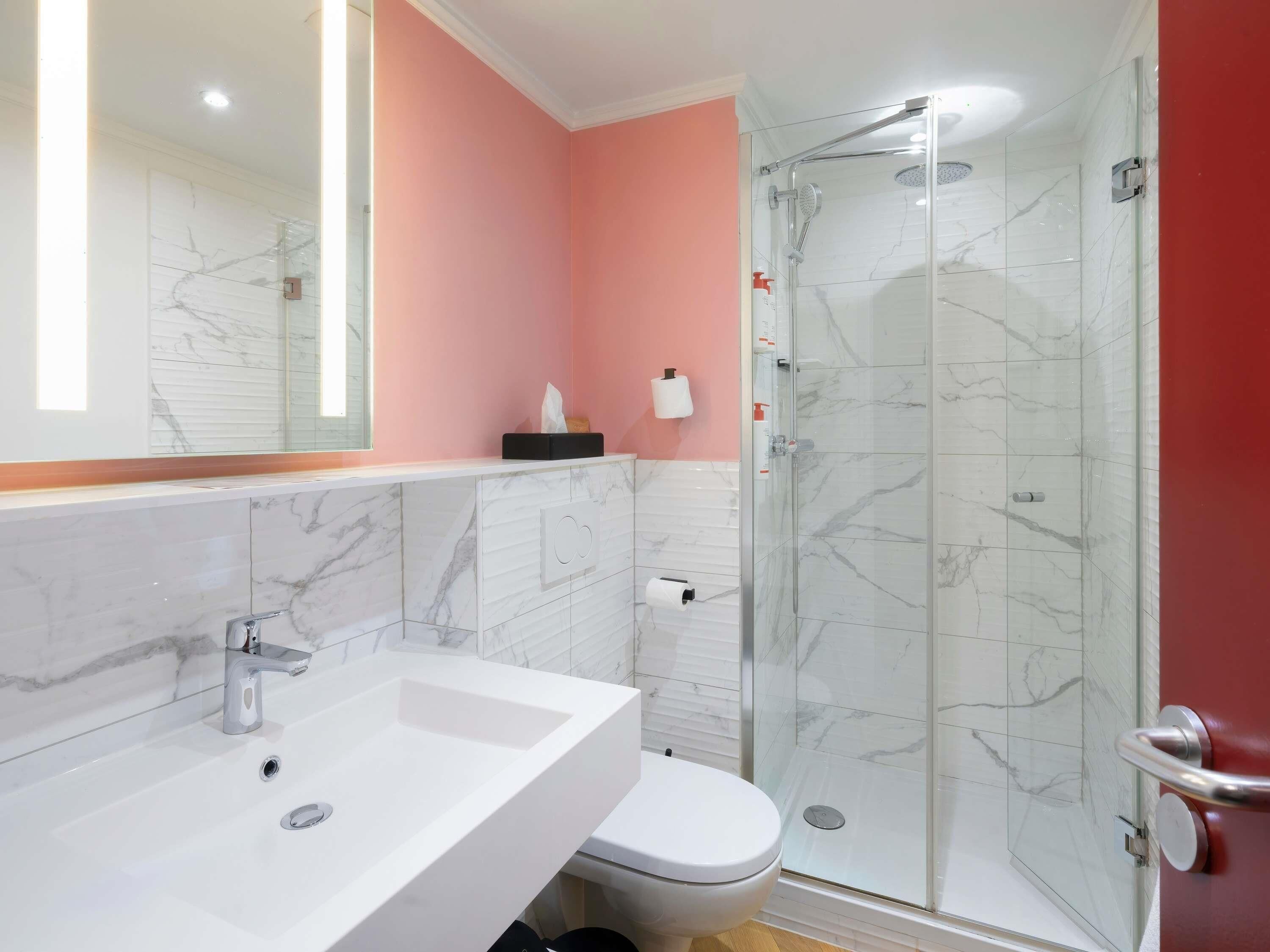 Une salle de bain avec un lavabo blanc, des toilettes et une douche à parois de verre.