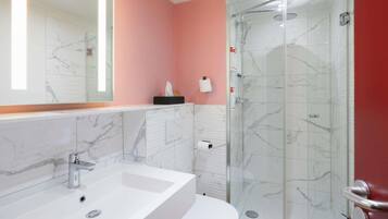 Une salle de bain avec un lavabo blanc, des toilettes et une douche à parois de verre.