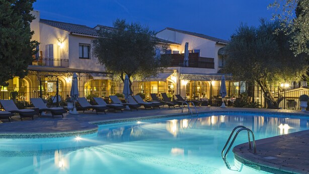 Zona de piscina con sillas de descanso y un edificio con terraza.