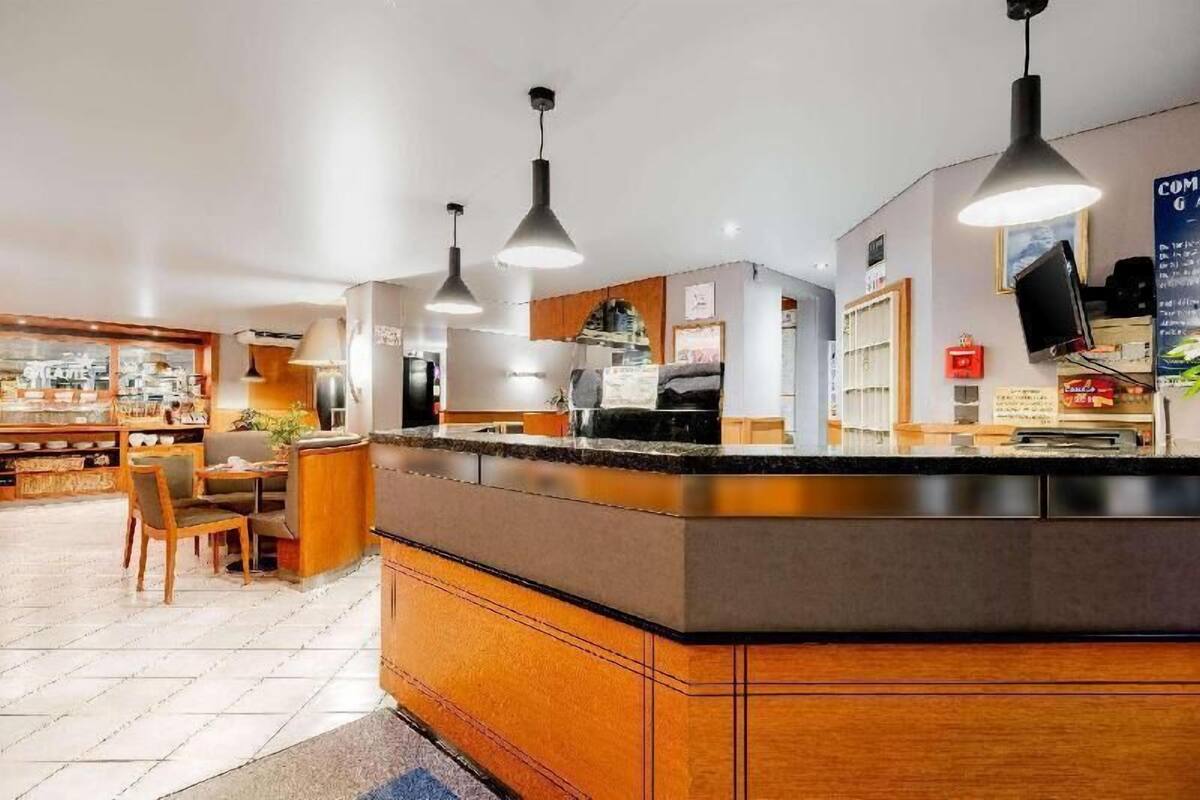 A hotel lobby with a reception desk, seating area, and a television mounted on the wall.