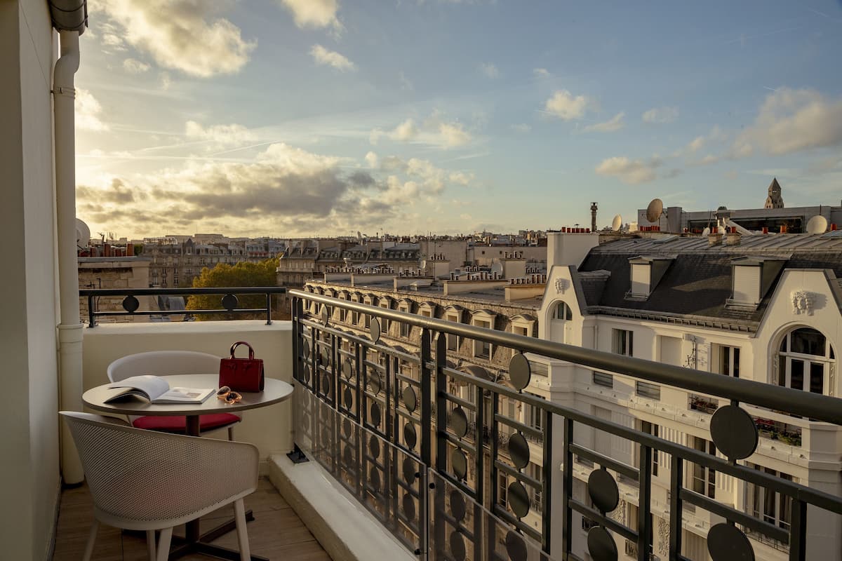 Ein Balkon mit Tisch, Stuhl und einer roten Handtasche.