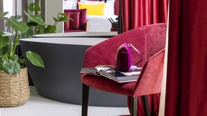 Una habitación moderna con una cama curvada, una silla roja con una computadora portátil y un espejo grande.