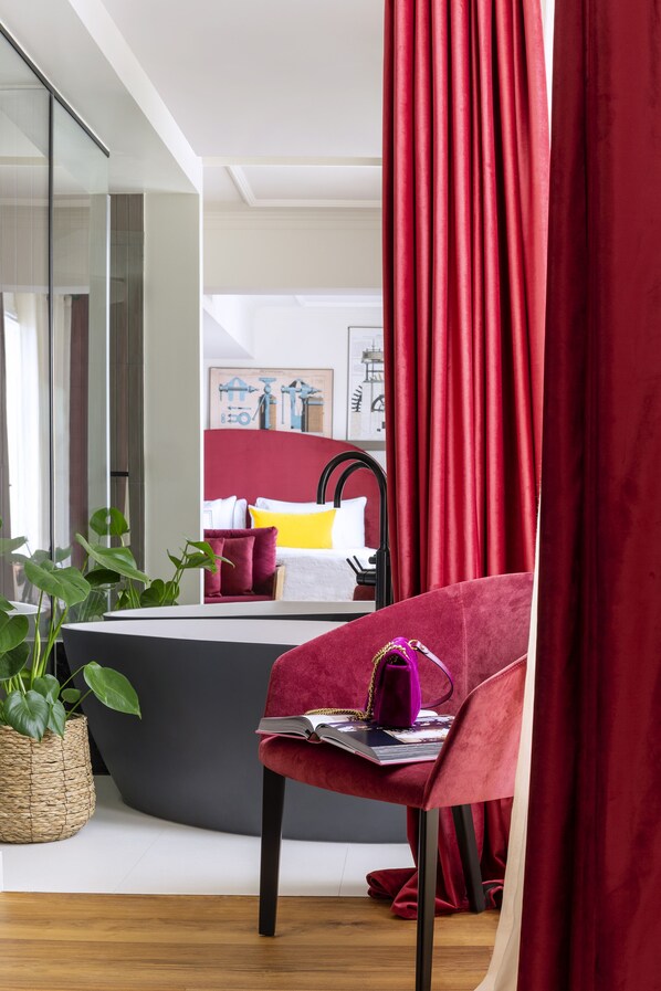 A modern room with a curved bed, a red chair with a laptop, and a large mirror. - Villa Marquis a Member of Melia Collection Tour Eiffel (Paris)