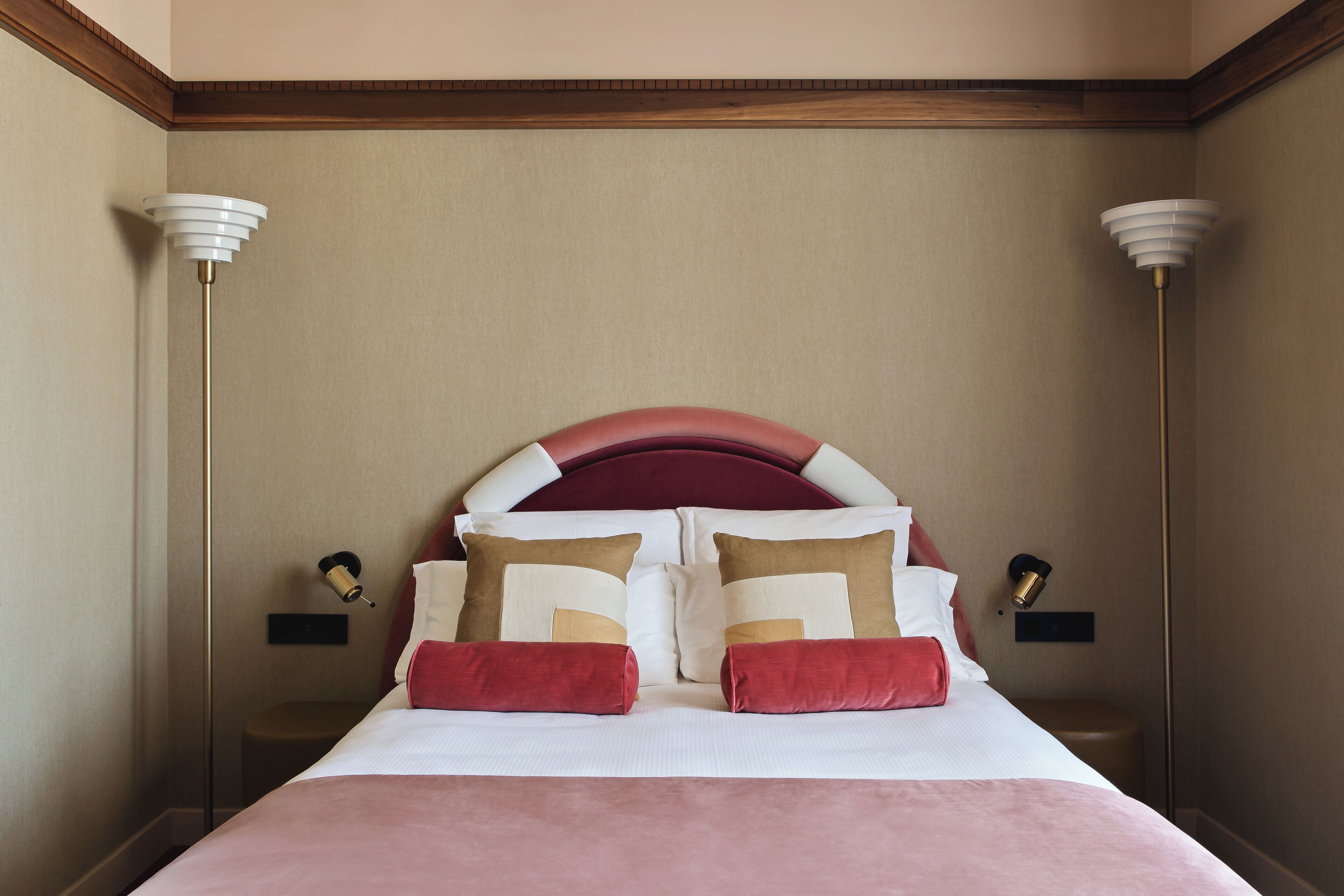 A hotel room with a large bed, two bedside lamps, and a wooden ceiling.