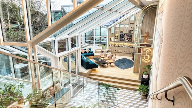 A modern interior with a glass atrium, wooden flooring, and a seating area with sofas and a coffee table. - Citadines Les Halles Paris (Paris)