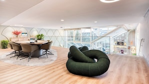 A modern interior with a round table, chairs, and a green bean bag chair. - Citadines Les Halles Paris (Paris)