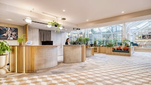 A modern reception area with a geometric patterned floor, a reception desk, and a large window providing a view of the outdoors. - Citadines Les Halles Paris (Paris)
