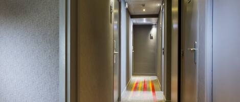 A hotel hallway with a carpet featuring red, yellow, and orange stripes. There is a sign on the wall indicating room numbers 6, 601-605, and 606-607.