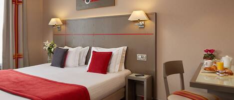 A hotel room with a large bed, bedside lamps, a small table with breakfast items, and a chair.