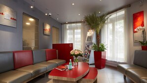 A modern waiting area with leather seating, a reception desk, and a large window providing natural light. - Hôtel Alizé Grenelle Tour Eiffel (Paris)