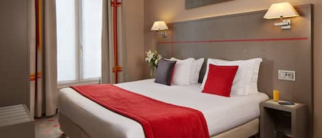 A hotel room with a large bed, two bedside lamps, a nightstand with a glass of orange juice, and a window with curtains.