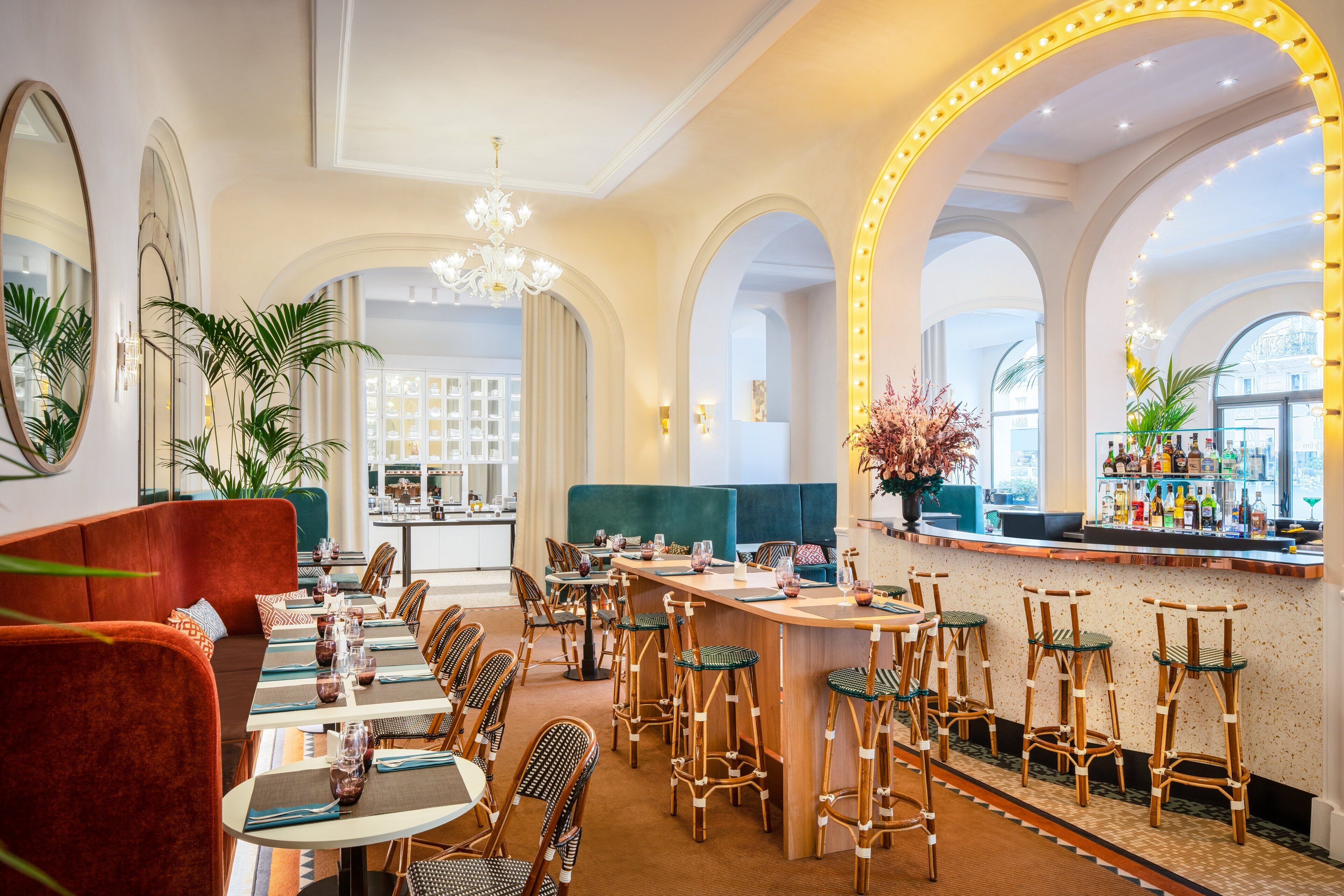 A restaurant with a bar area, high ceilings, and arched windows.