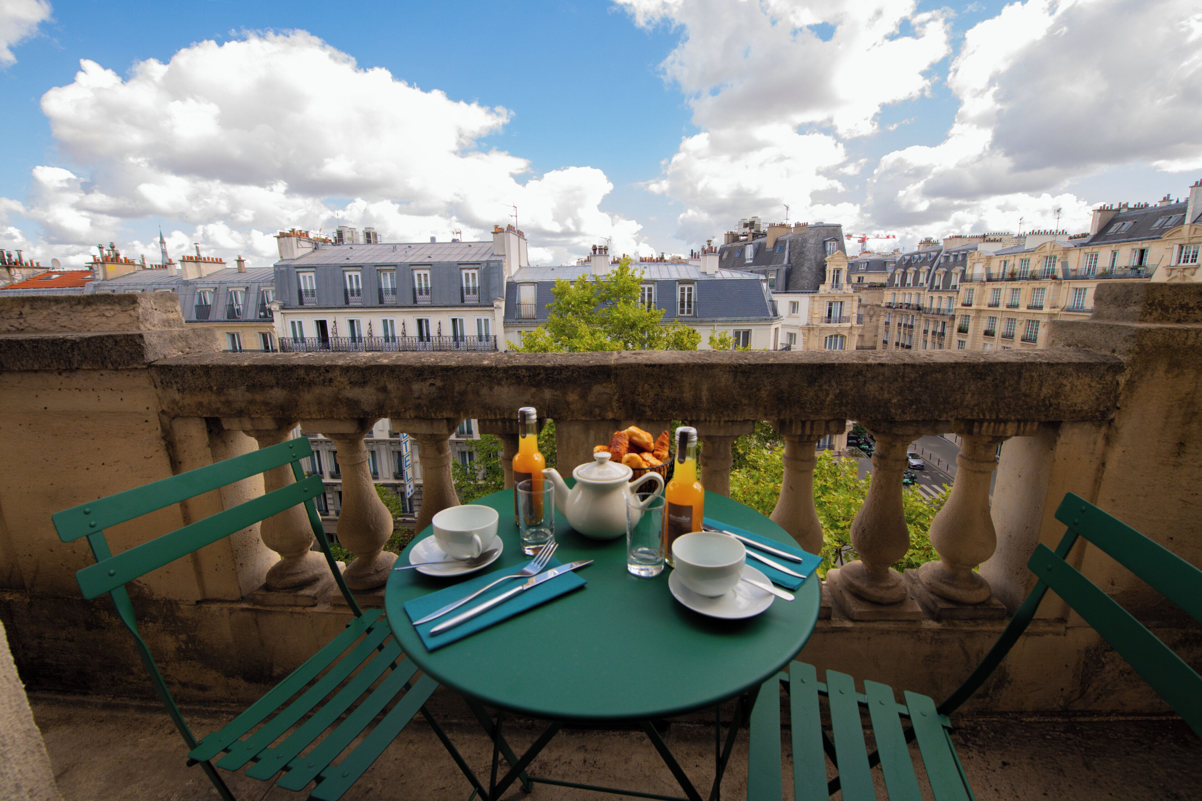 A table set for breakfast with a view of buildings in the background.