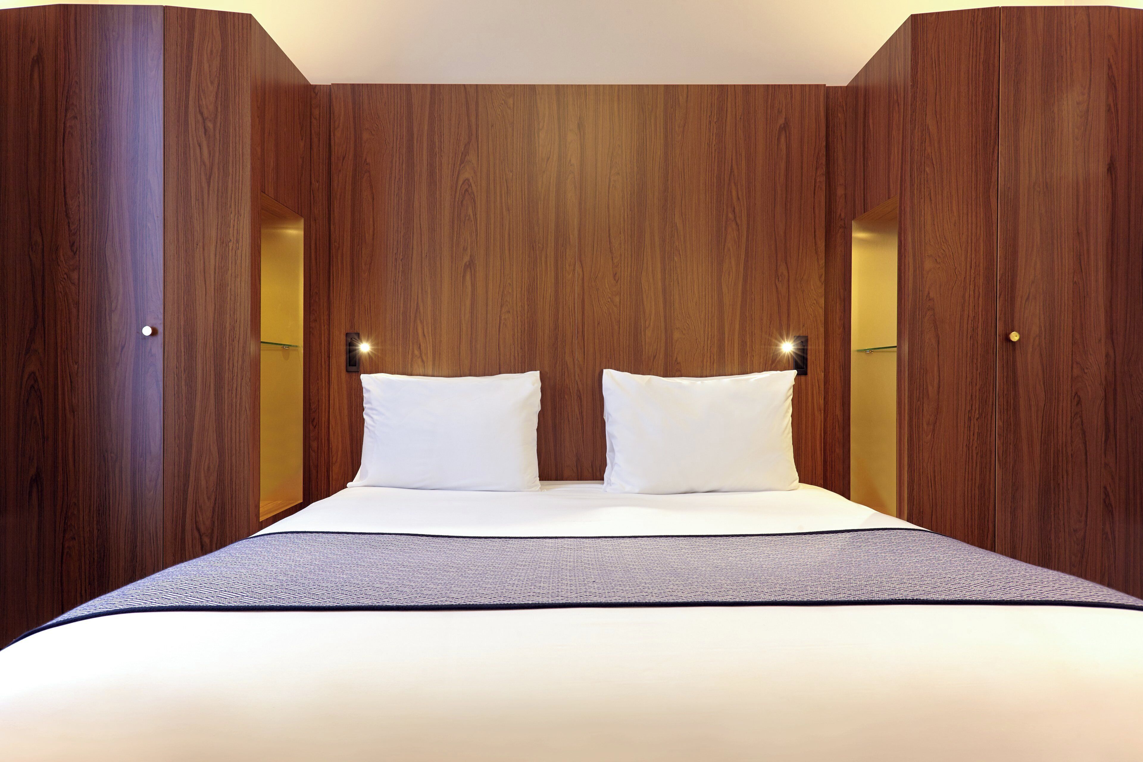 A bedroom with a large bed, wooden paneling, and two bedside lamps.