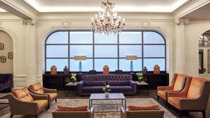 A spacious lobby with a large arched window, a chandelier, and a seating area with sofas and armchairs. - Holiday Inn Paris - Gare de Lyon Bastille by IHG (Paris)