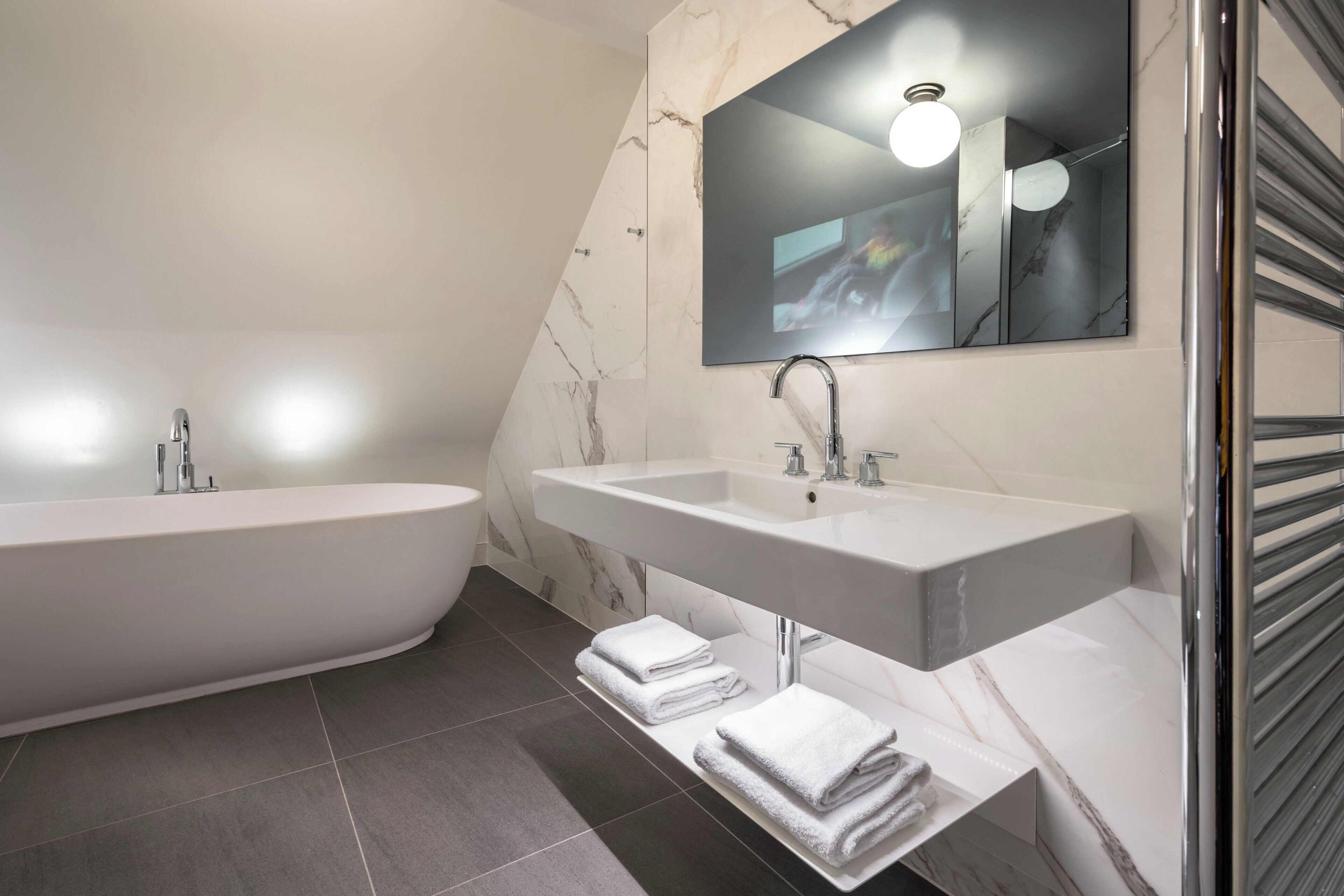 Une salle de bain moderne avec une baignoire sur pieds, deux vasques et un grand miroir.