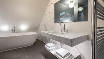 Une salle de bain moderne avec une baignoire sur pieds, deux vasques et un grand miroir.