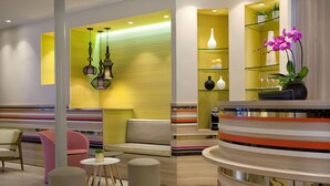 A modern lobby with a seating area, a reception desk, and decorative lighting. - Hotel Berne Opera (Paris)