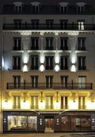 Un hotel de varios pisos con balcones iluminados y una entrada a nivel de calle.
