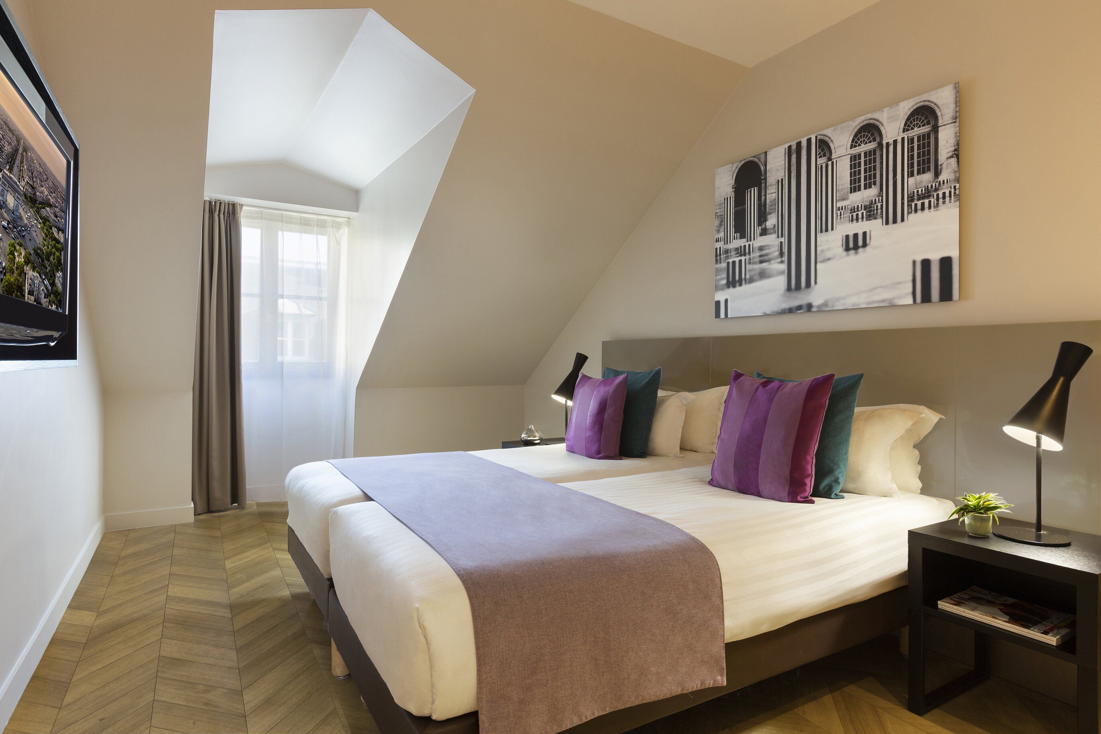 Een moderne slaapkamer met een groot bed, een nachtkastje, een lamp en een stadsgezichtschilderij aan de muur.