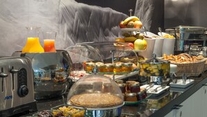 Een buffet met diverse gerechten, een broodrooster en een glas sinaasappelsap.
