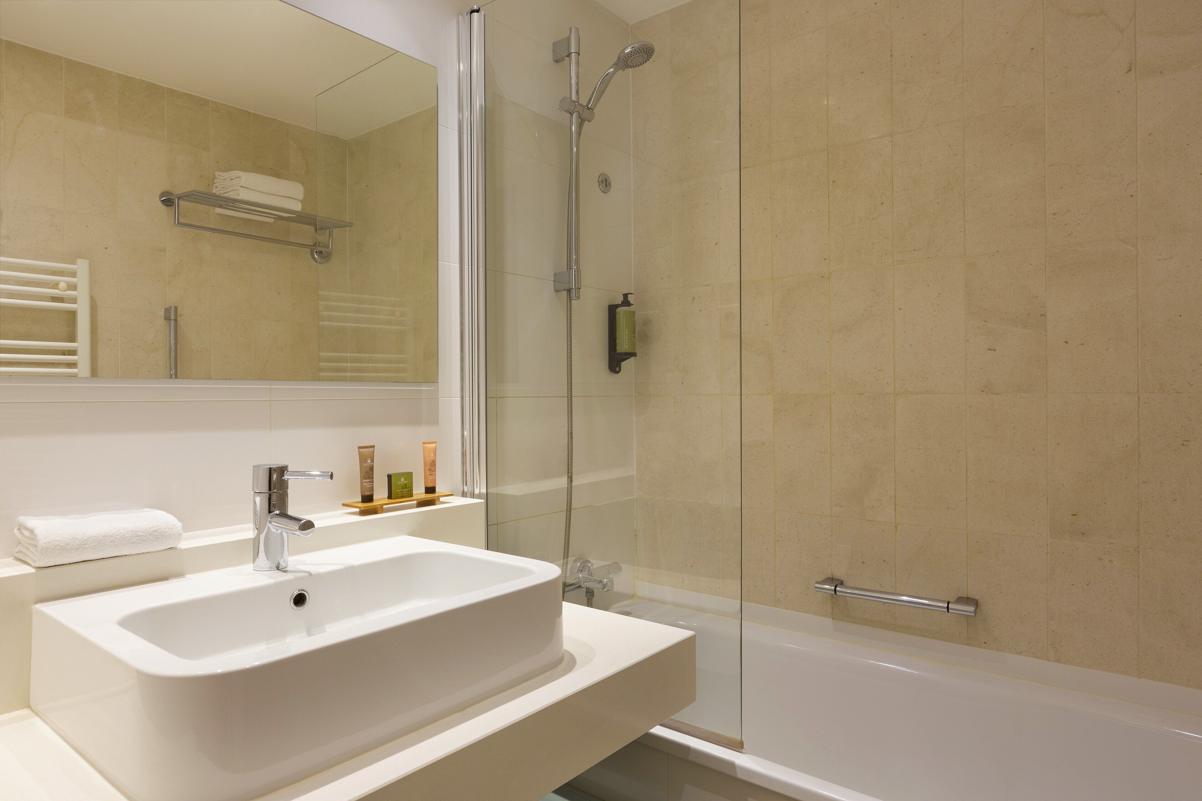 A modern bathroom with a large sink, mirror, and glass-enclosed shower.