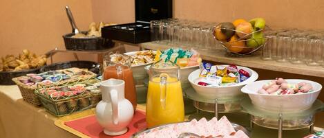 A buffet with various food items, including meats, fruits, and beverages.