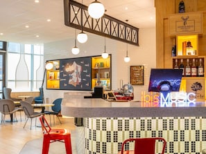 A modern bar area with a central counter, hanging lights, and a map on the wall. - ibis Paris CDG Airport (Tremblay-en-France)