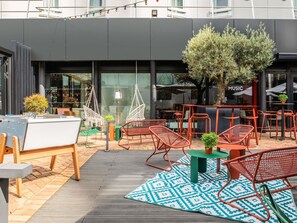 Un espace extérieur aménagé avec des chaises et des tables, un tapis à motifs et un arbre.