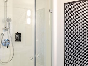 Une cabine de douche en verre dotĂ©e dâun pommeau de douche Ă main, dâun panneau de commande fixĂ© au mur et dâune porte de douche Ă texture.