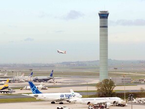 Airplanes are parked on the airport tarmac, overseen by the control tower.