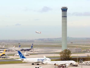 Airplanes are parked on the airport tarmac, overseen by the control tower.