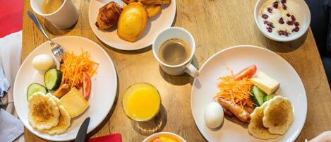 A breakfast setting with various dishes, including pastries, fruits, and beverages.