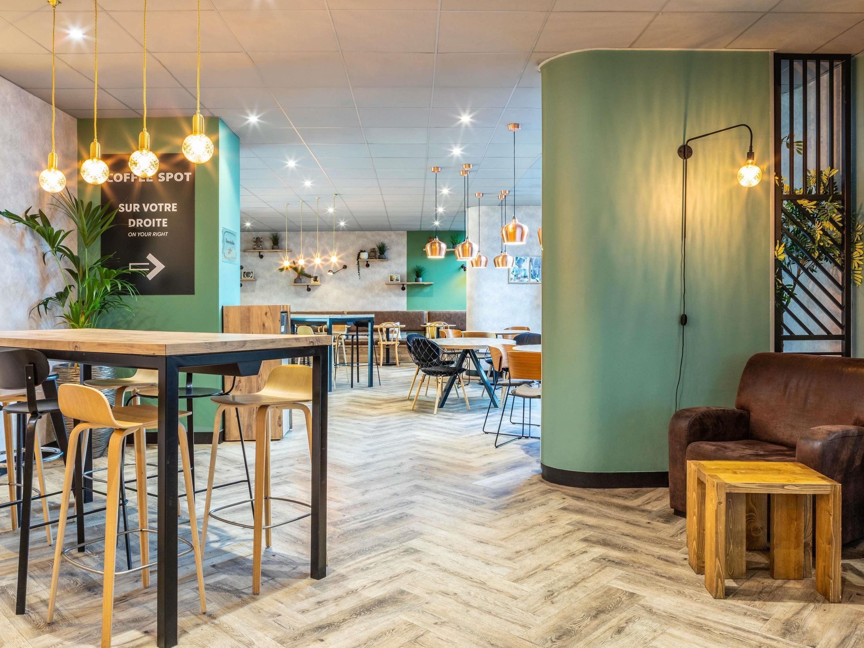 L’intérieur d’un café moderne, avec des meubles en bois, des suspensions décoratives et un parquet disposé en chevrons.