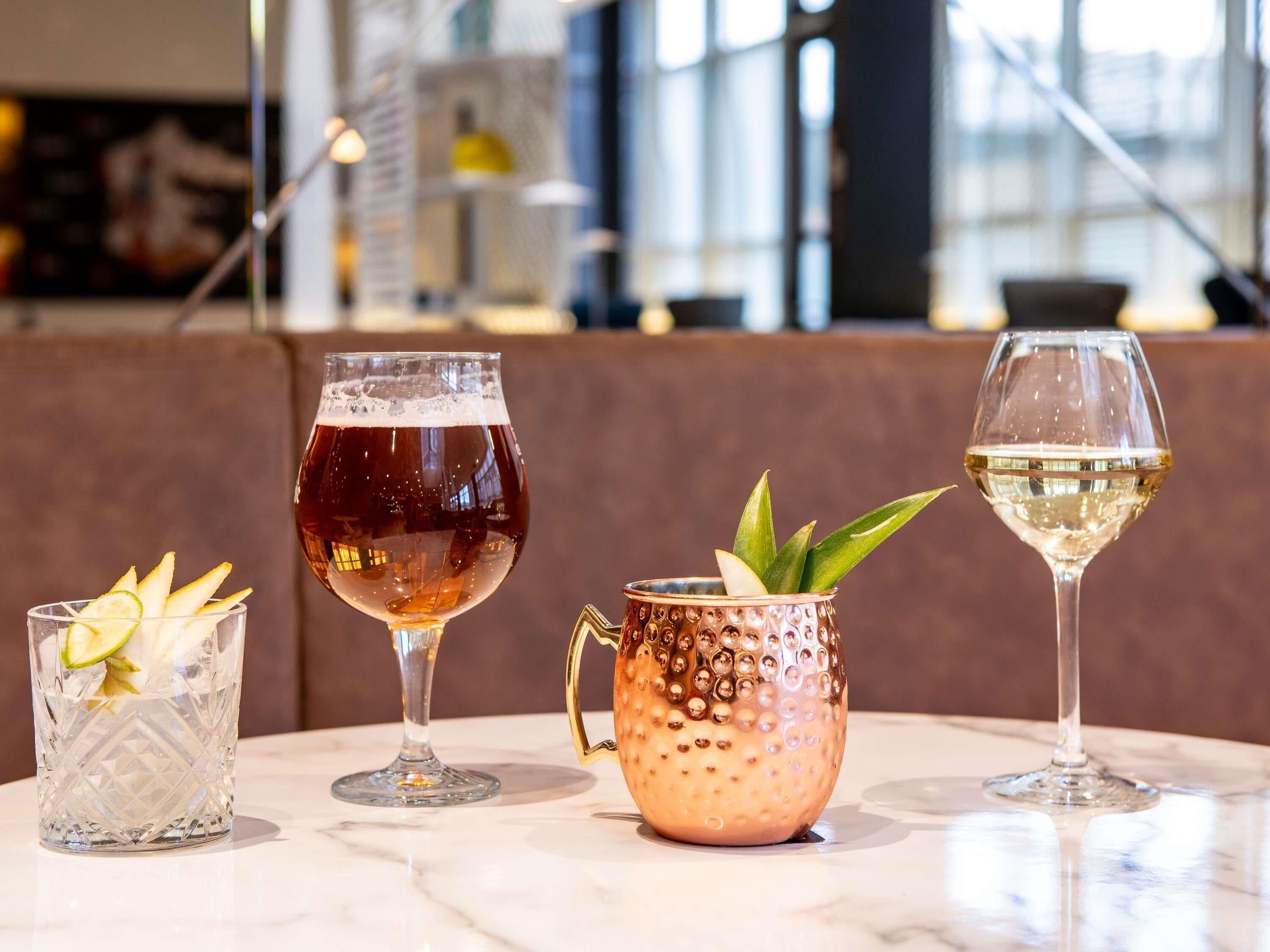 Tres vasos de bebidas sobre una mesa de mármol en un interior moderno.