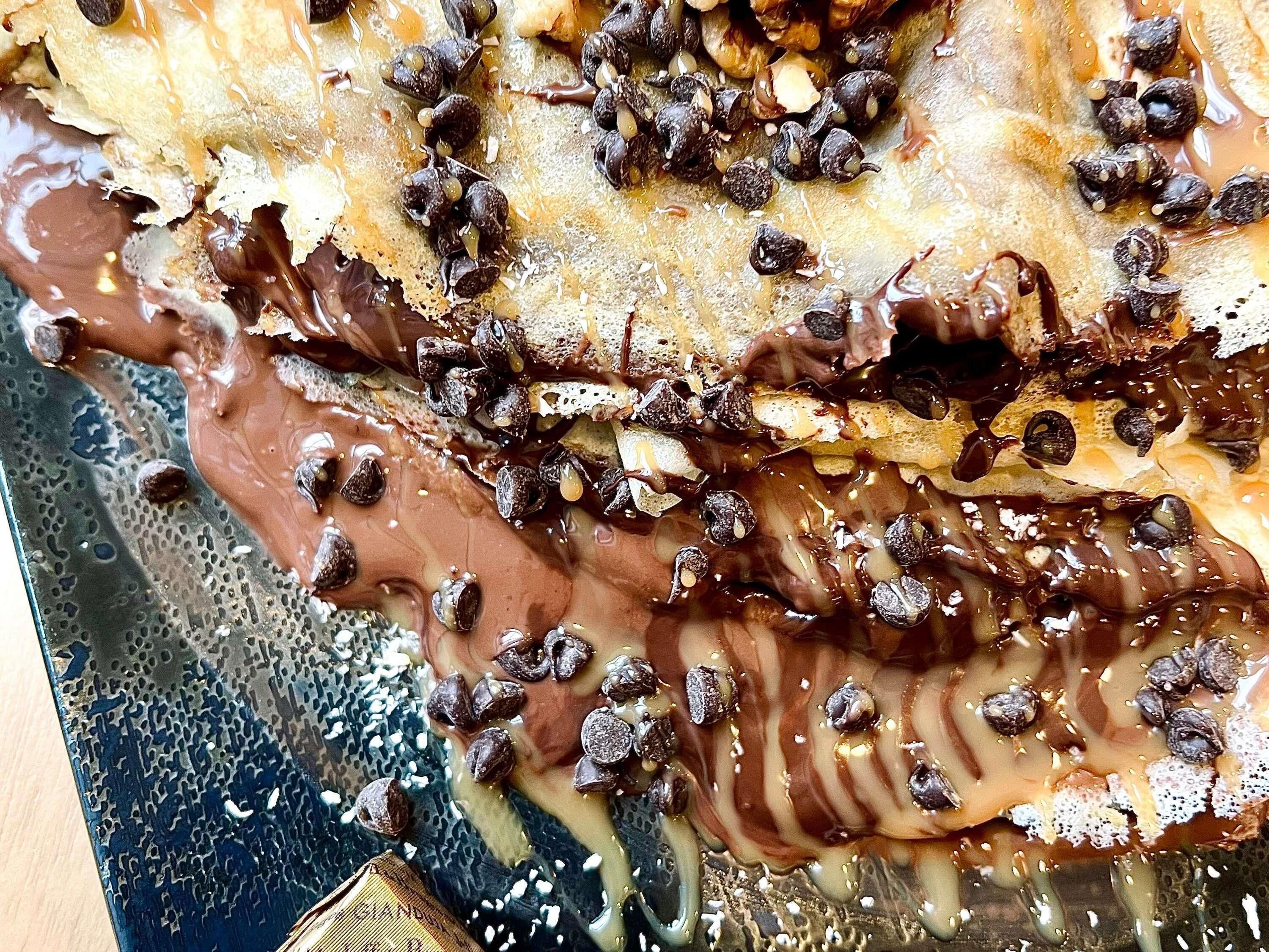 A close-up of a chocolate-covered dessert with nuts.