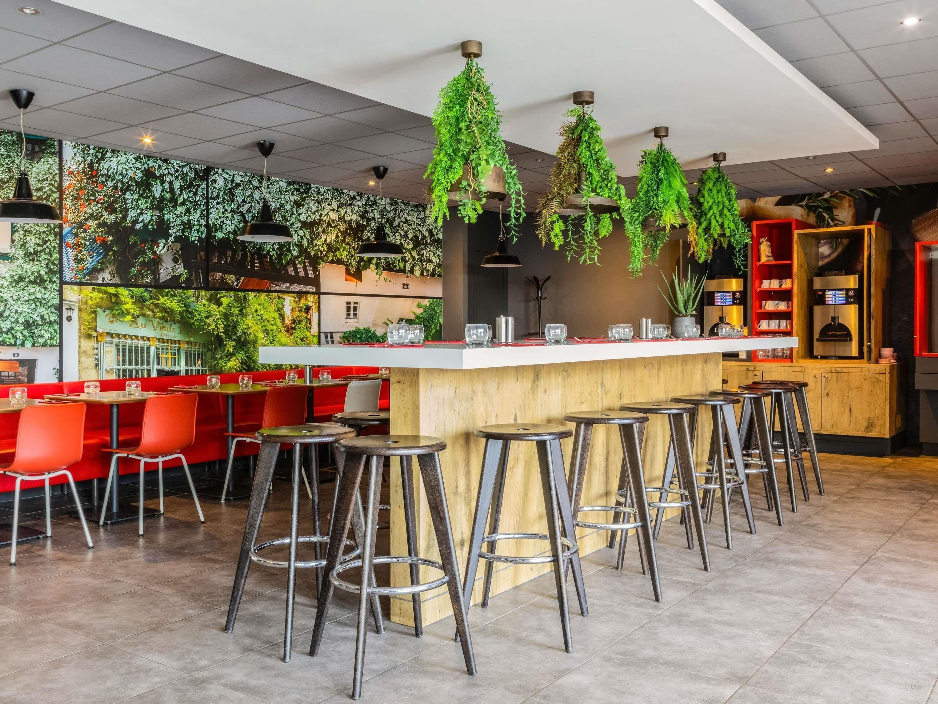 A modern bar area with stools, a counter, and hanging greenery.