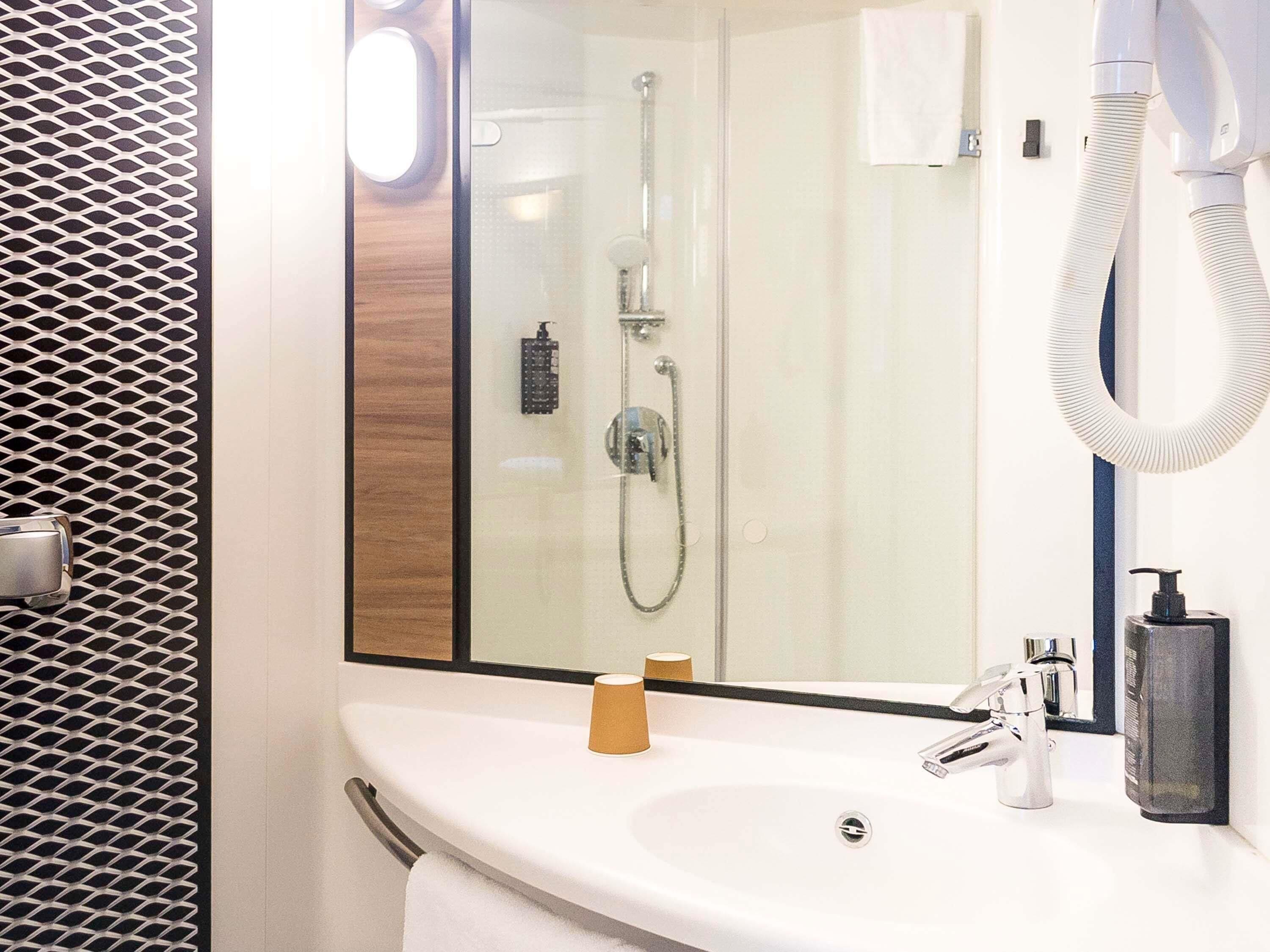 Un baño moderno con cabina de ducha de vidrio, un lavabo blanco y un perchero para toallas.