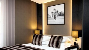 Une chambre d’hôtel avec un lit, deux lampes de chevet, un tableau encadré au mur et une fenêtre avec des rideaux.